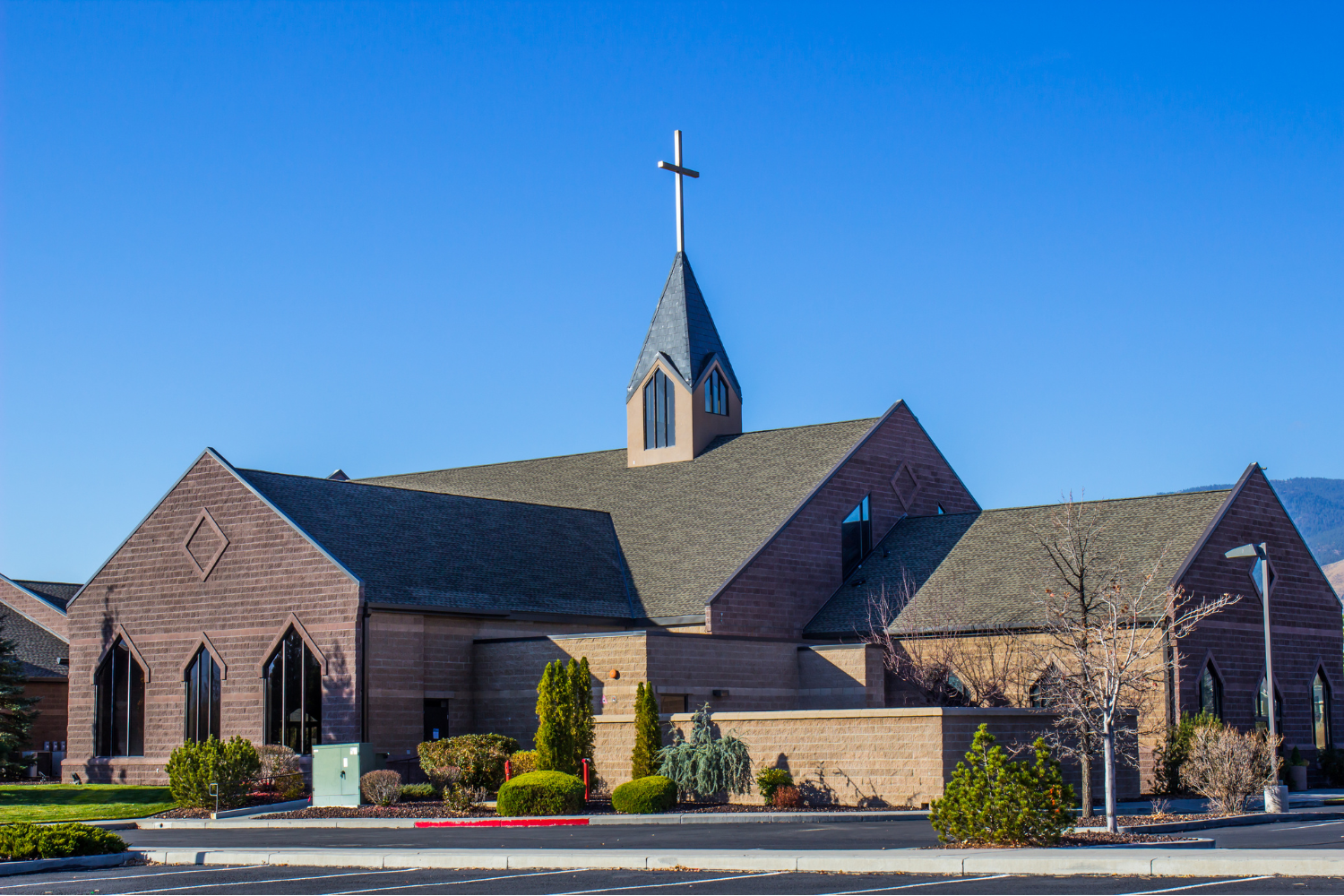 Modern church building with cross on the steeple under a clear blue sky, symbolizing church challenges faced by congregations today.