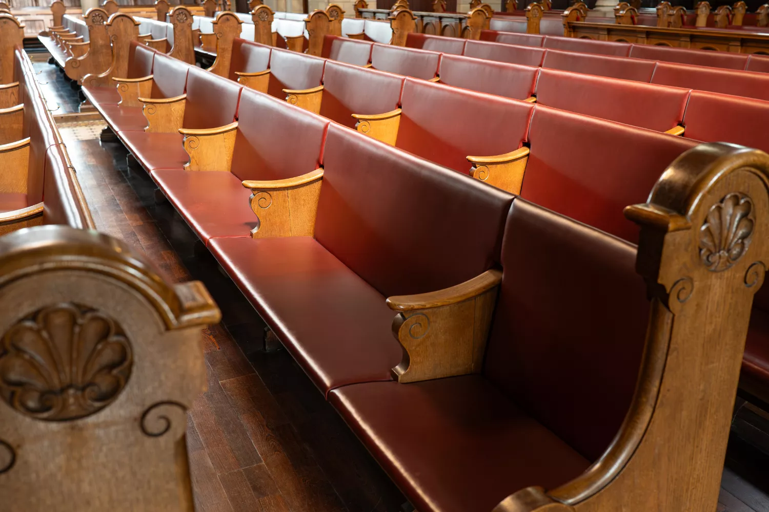 Empty church pews with polished wood and red cushions, symbolizing reflection and growth from ministry lessons.