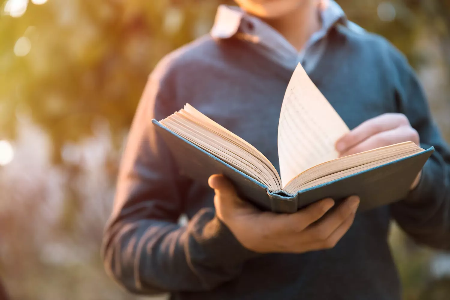 A pastor walking outside with an open book, preparing to preach the Word.