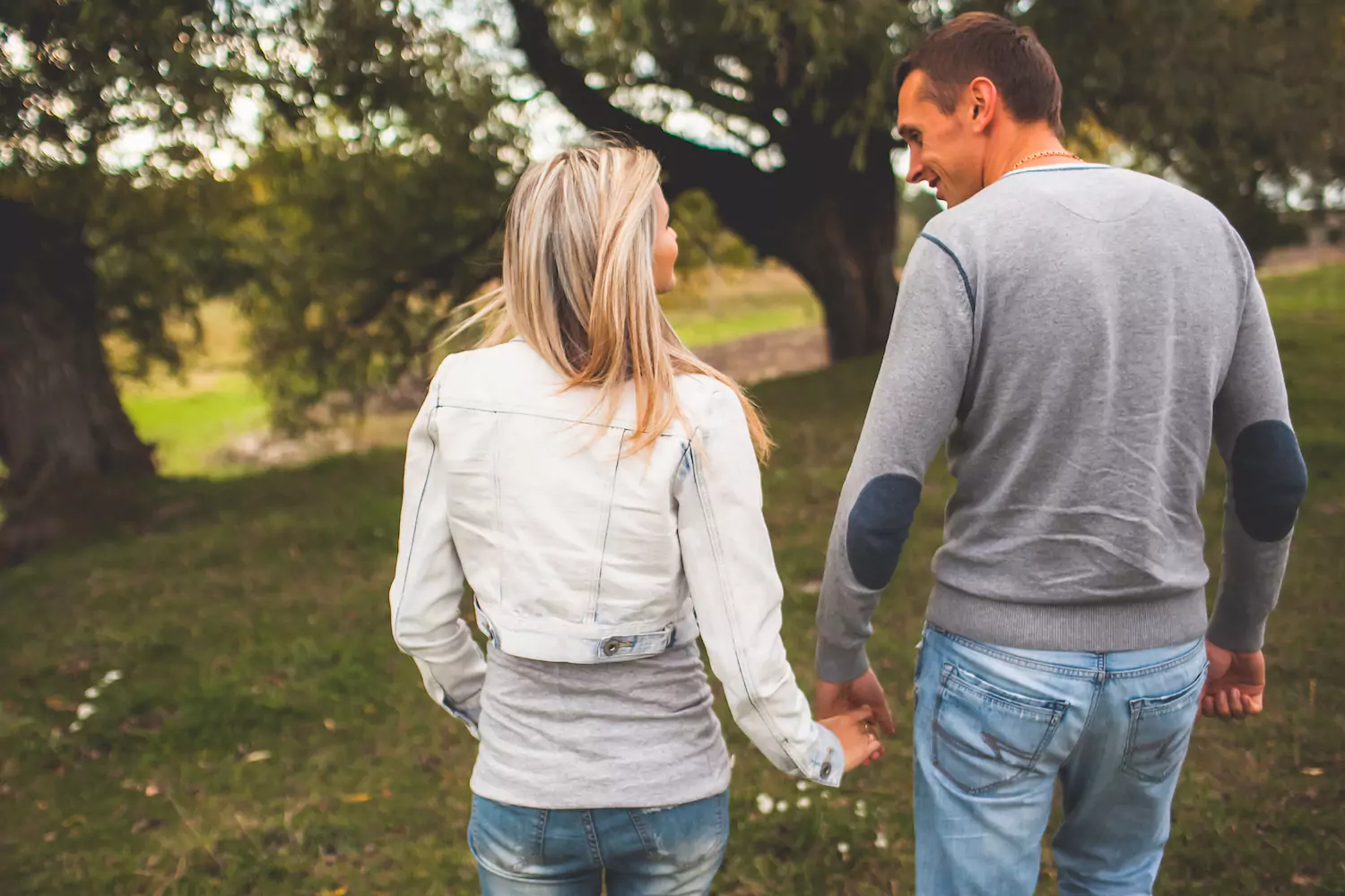 A photo of a married couple walking hand-in-hand through a forest.
