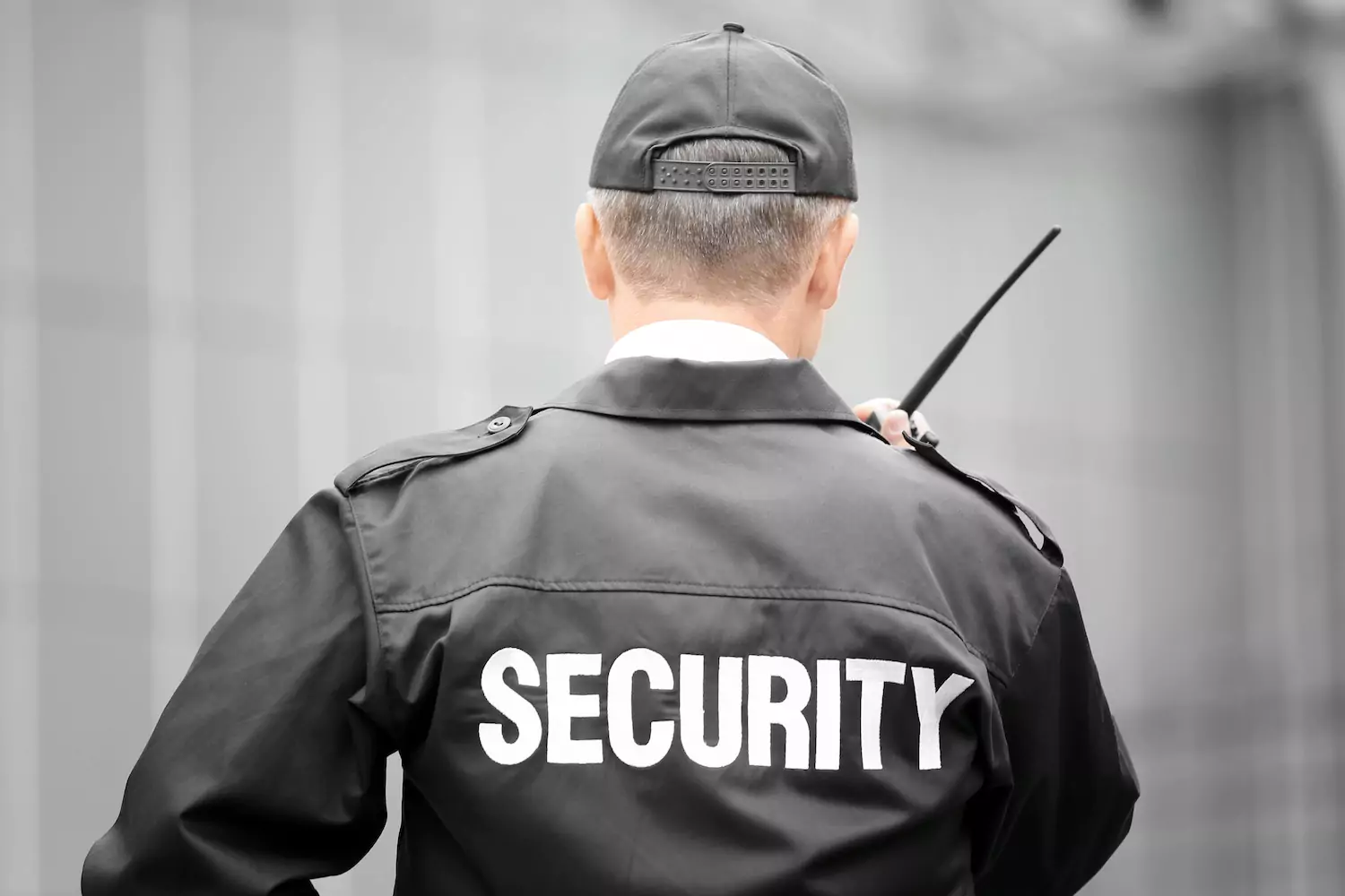 The backside of a security guard who is talking into a walkie talkie
