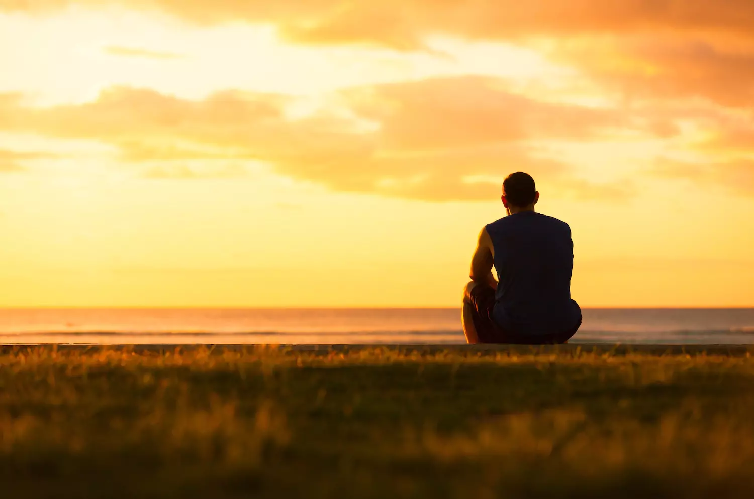 Man sitting while looking at the sunset