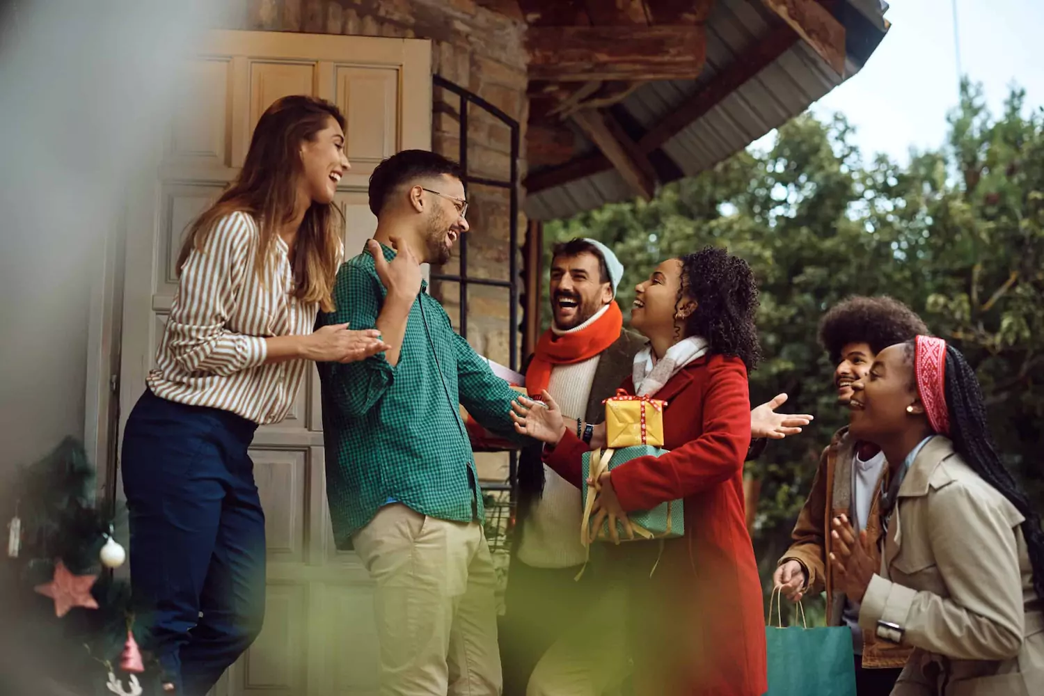 a young couple invites a group of festively-dressed friends into their home, practicing hospitality during the holidays