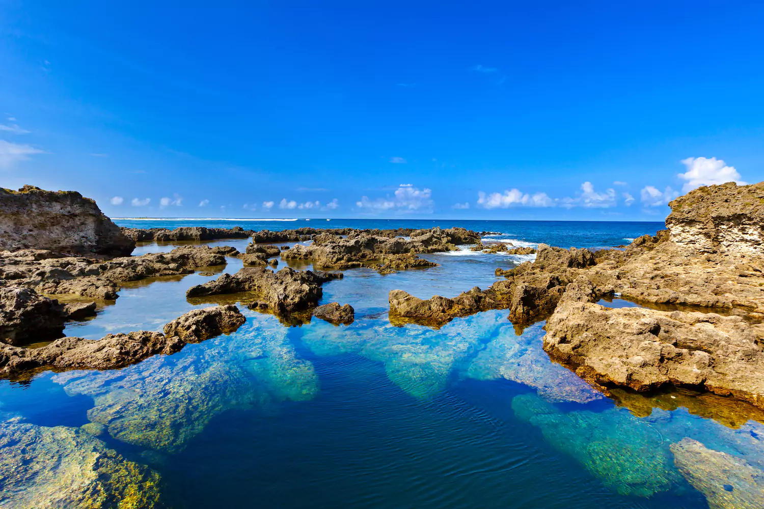 A photo of crystal clear blue waters and a clear blue sky in the New Hebrides Mountains.
