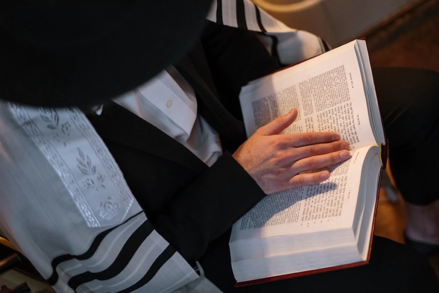 Close-up of a Jewish man in traditional clothing reading from the Torah.