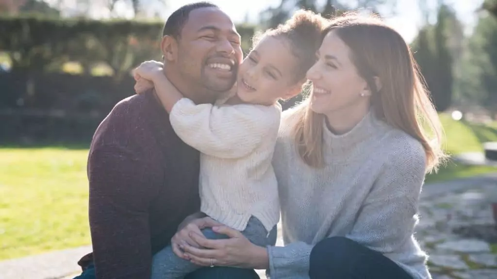 a man and woman hug a child together