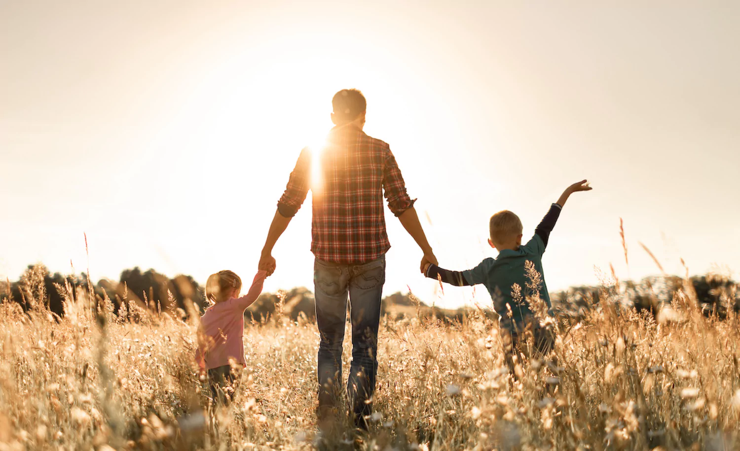 a pastor walks with his two pk children in a field
