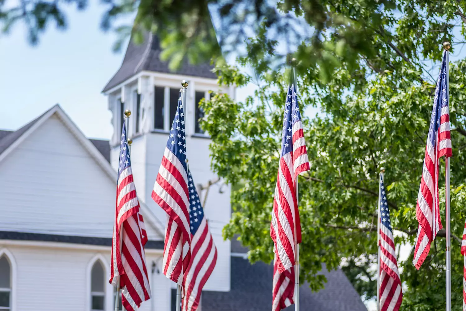 A white church with American flags outside, symbolizing the mixing of patriotism and worship.