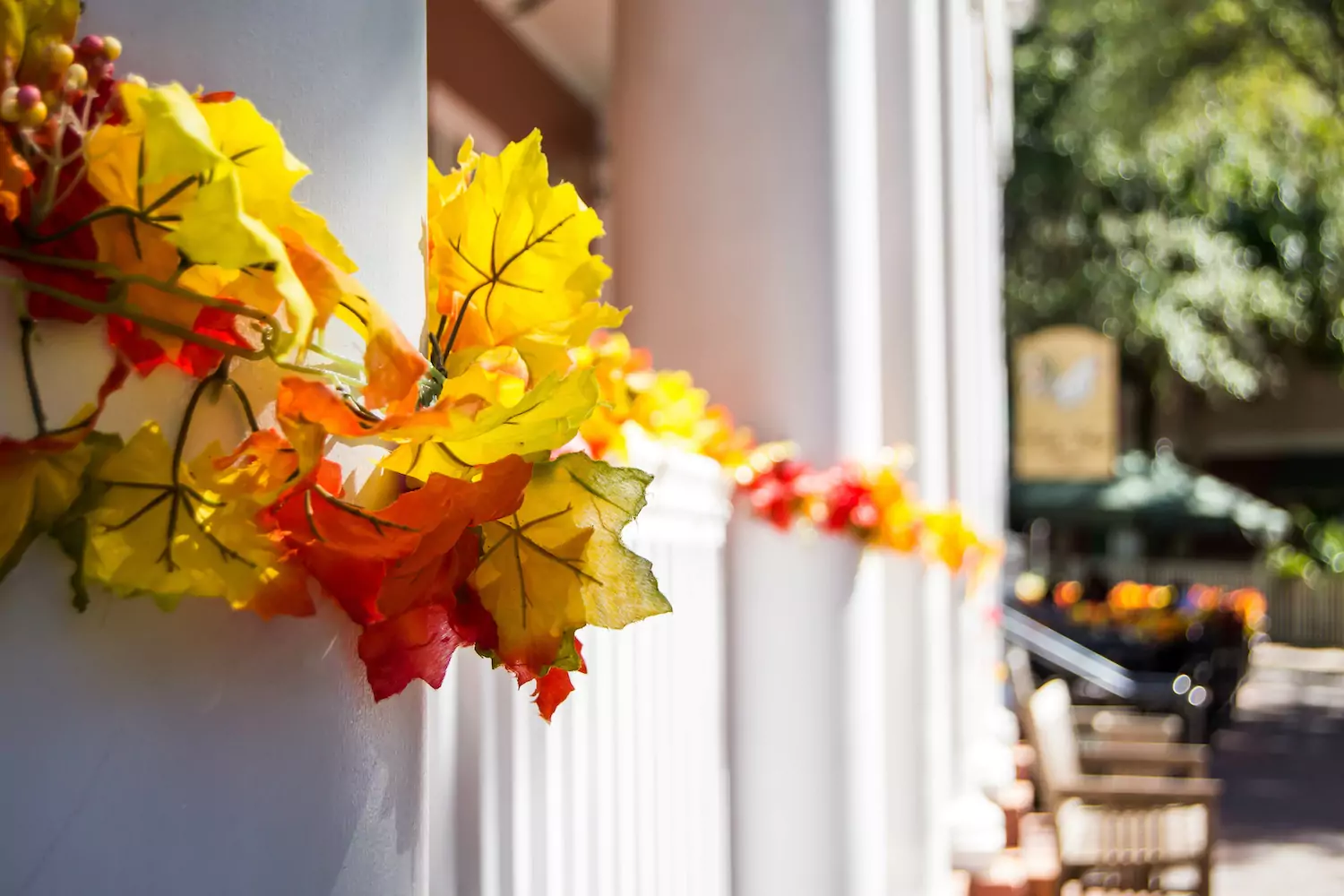 a long front porch decorated with warm leaves for Thanksgiving