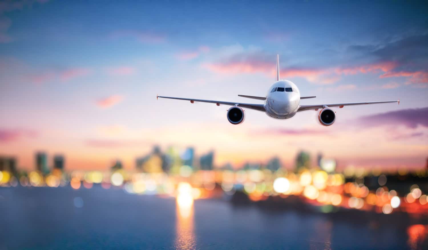 An airplane flies away from a bright city at night.