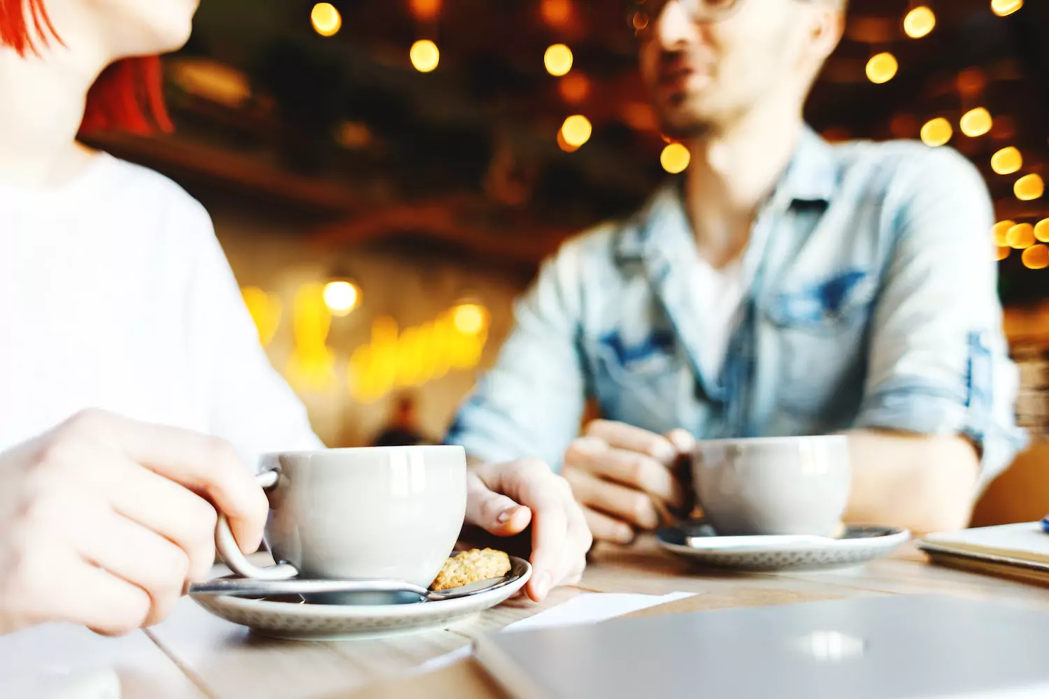 A man and a woman sit together over coffee, resolving conflict.