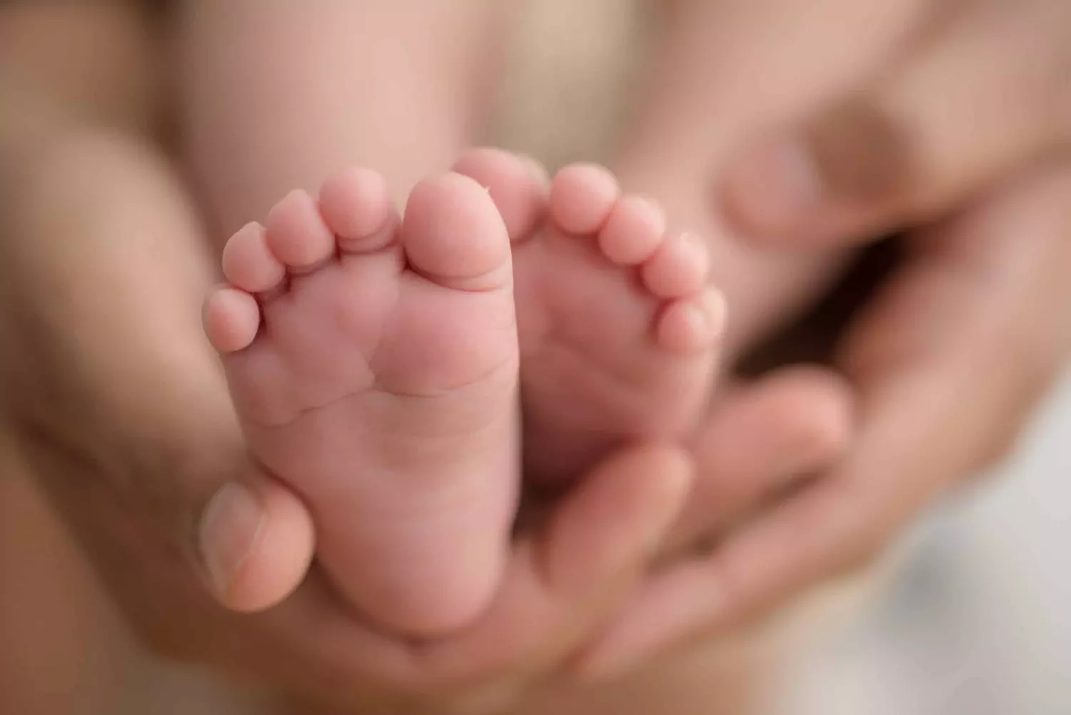 A mother holds her baby's feet in her hands.