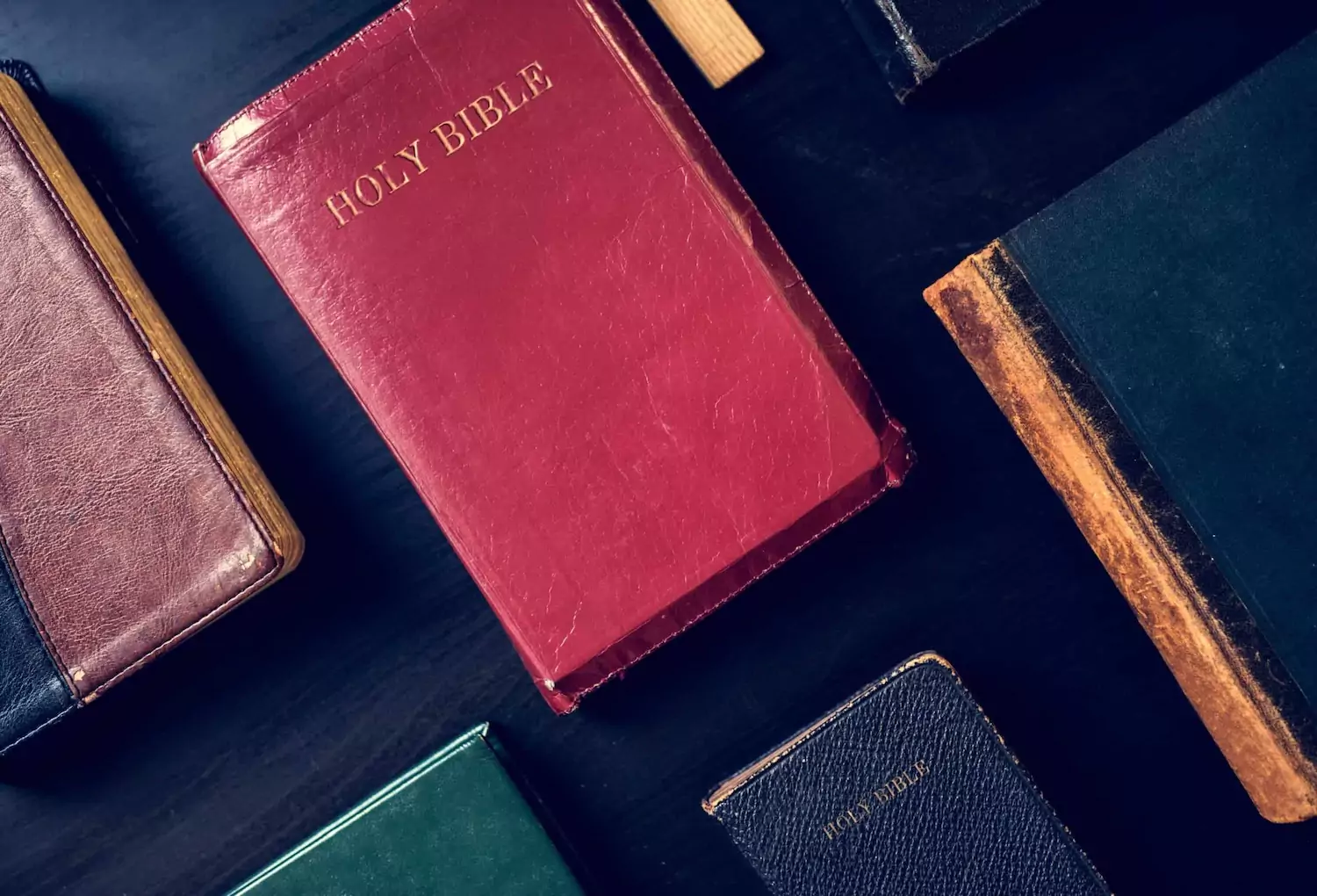 A table covered with Bibles of varying colors.