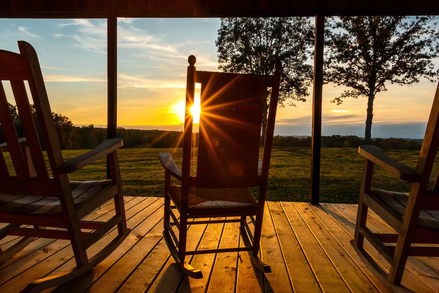Three rocking chairs on a front porch at sunset where a pastor might rest.