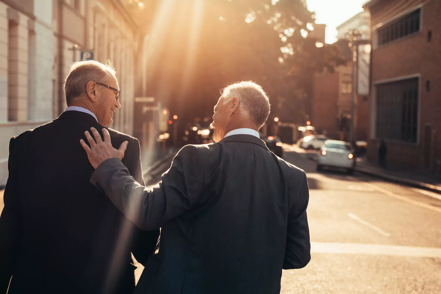 Two pastors walk together down the street as the sun shines down on them.