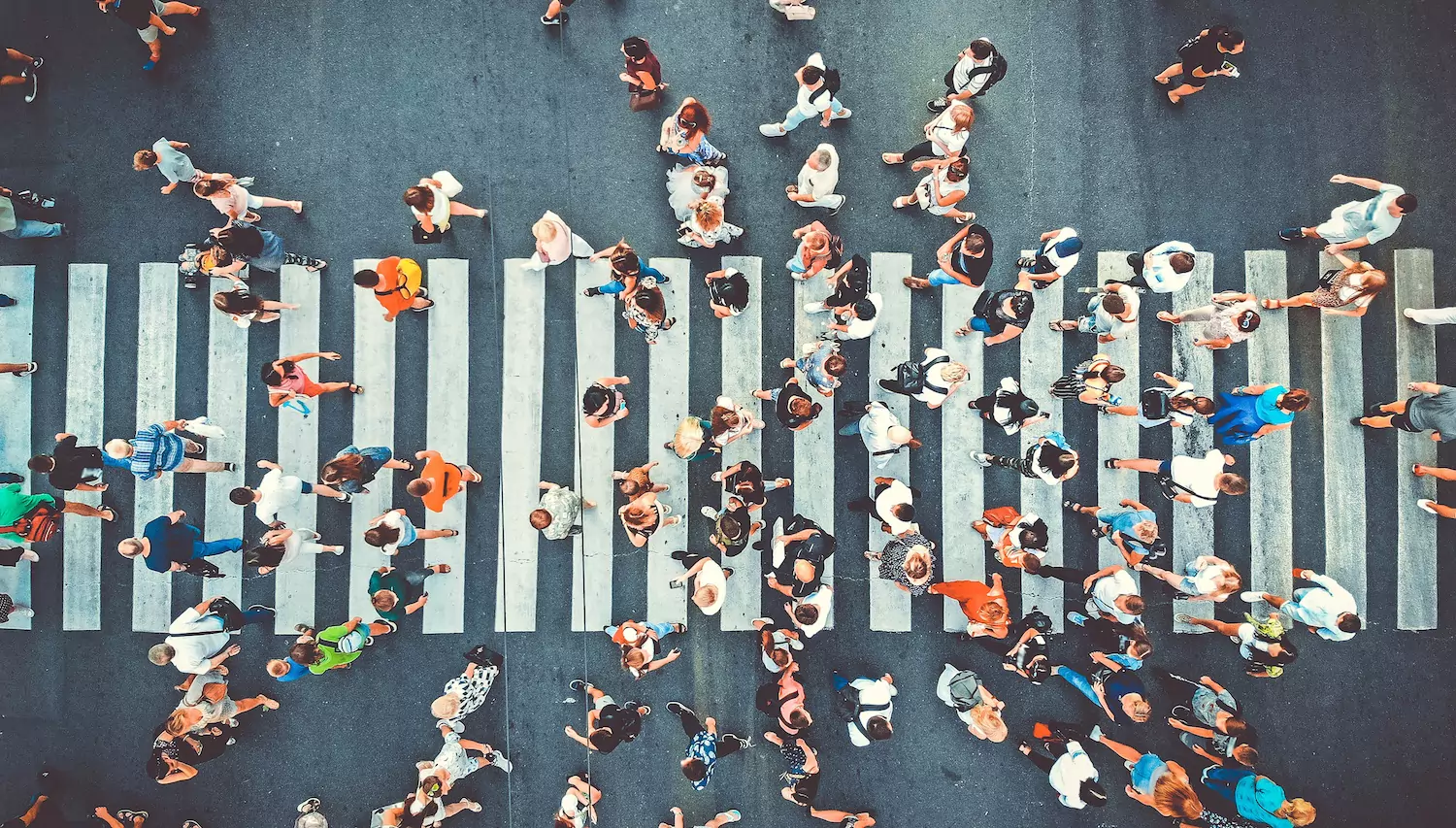A crowd of people cross a crosswalk.