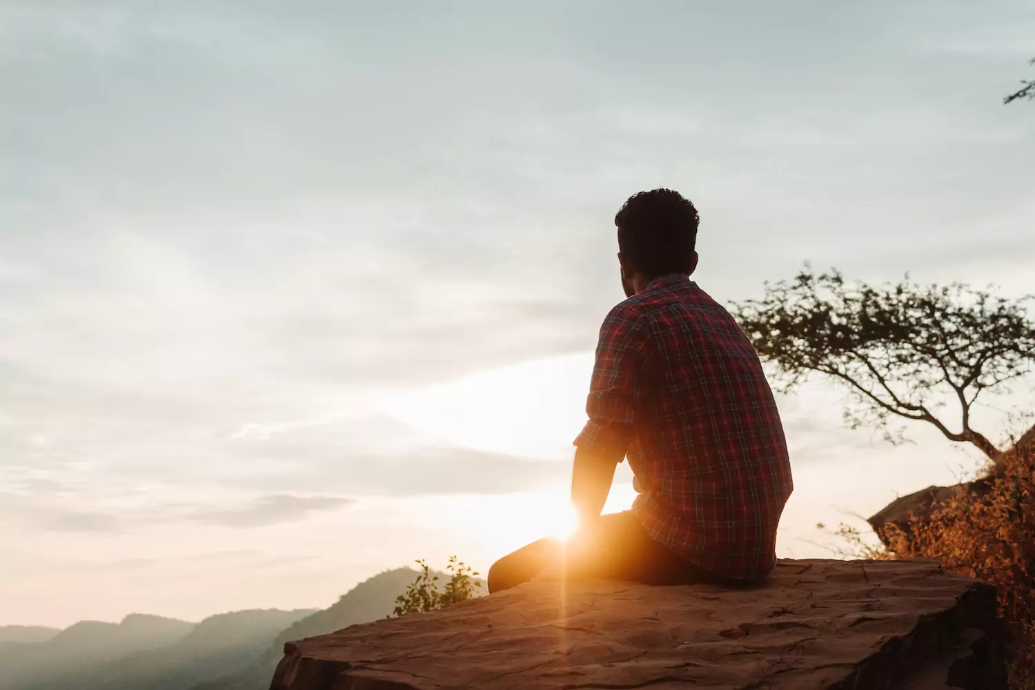 A pastor sits on the edge of a cliff as the sun begins to set, watching his life and doctrine.