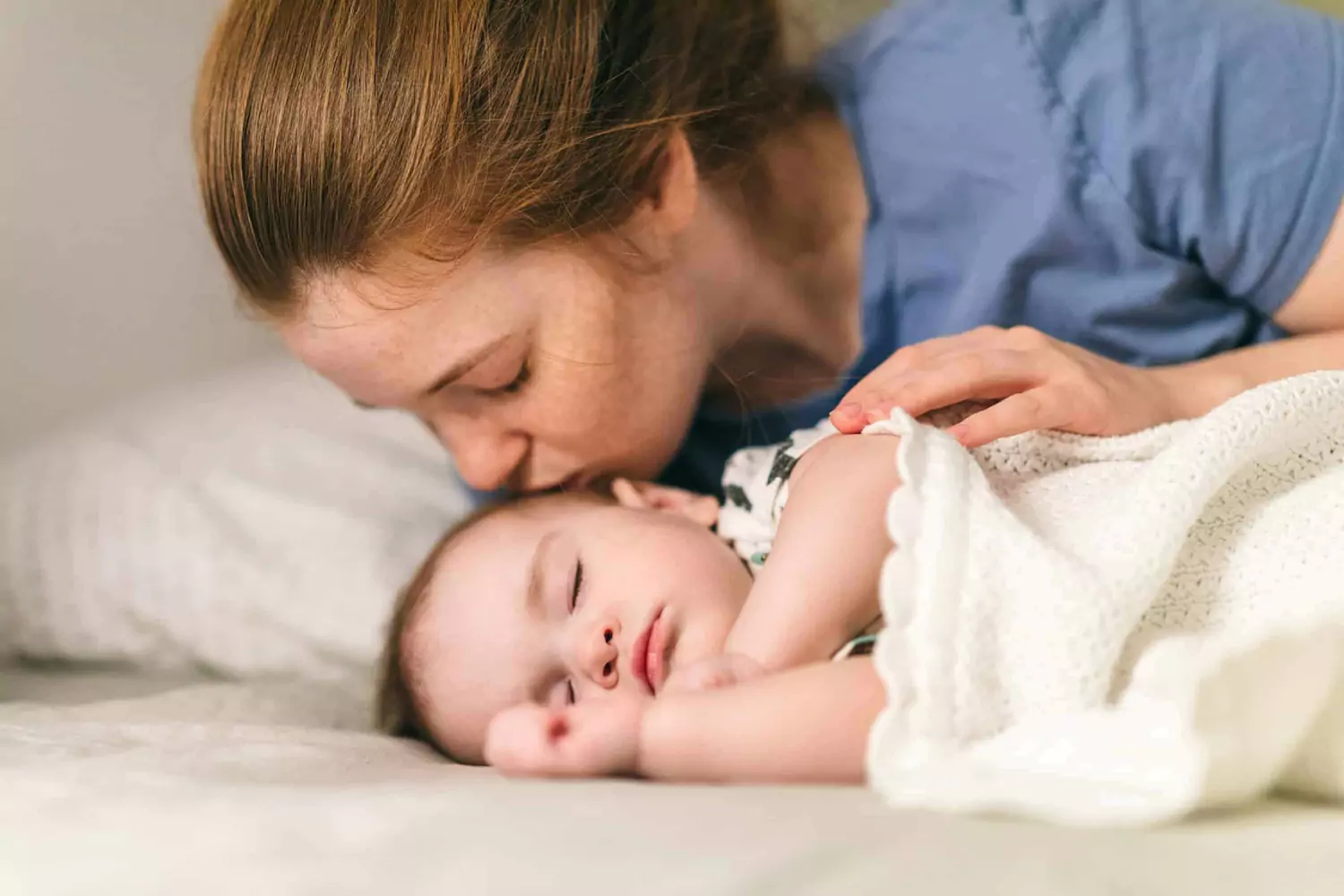 A mother kisses her baby.