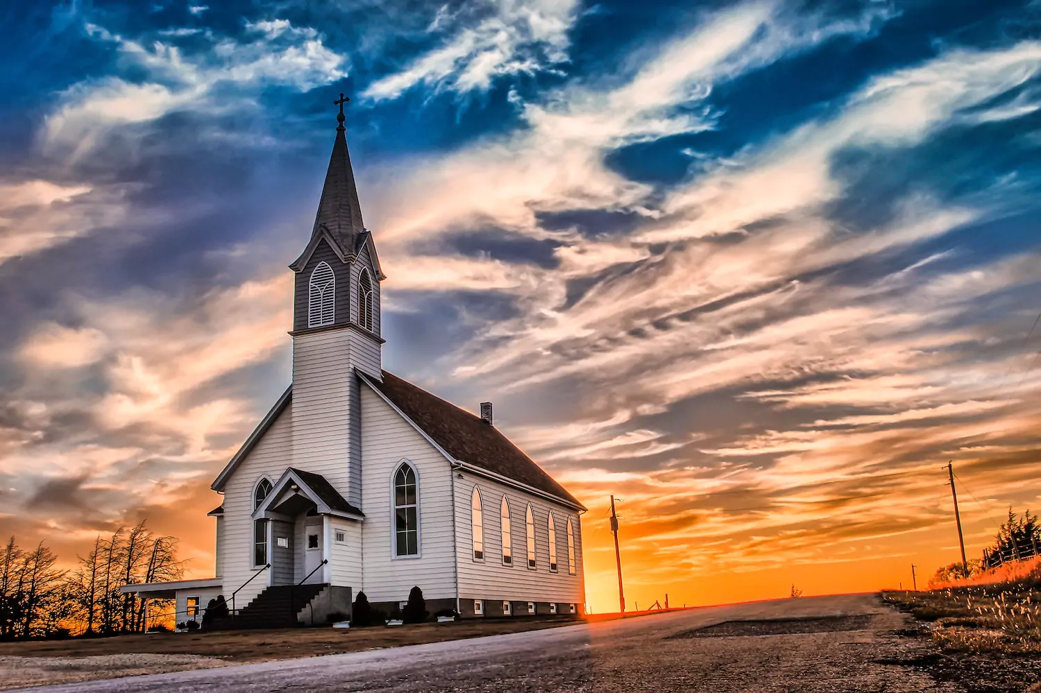 A white church with a steeple at sunset.
