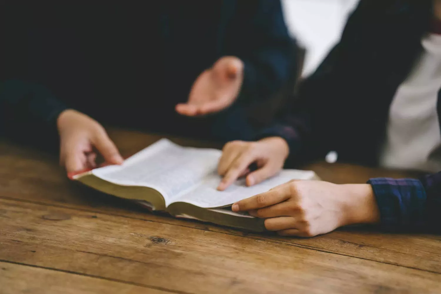 A pastor teaches a church member from the Bible, delegating so that they can do the same.