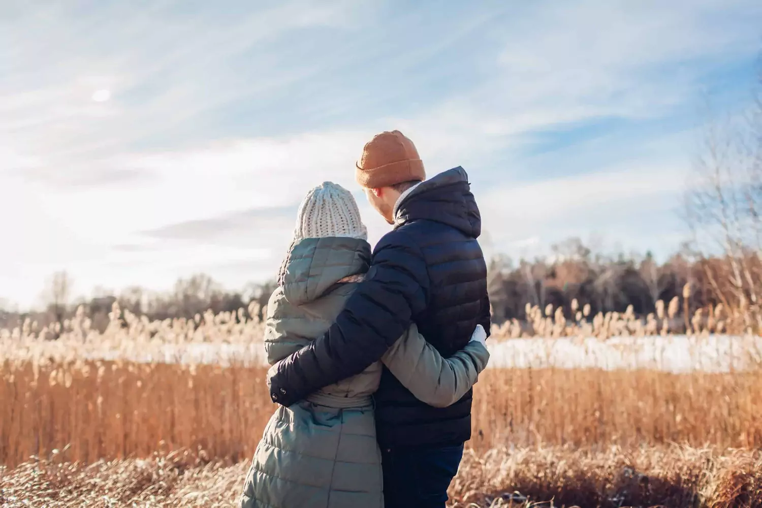 A pastor and has wife stand outside with their arms around one another.