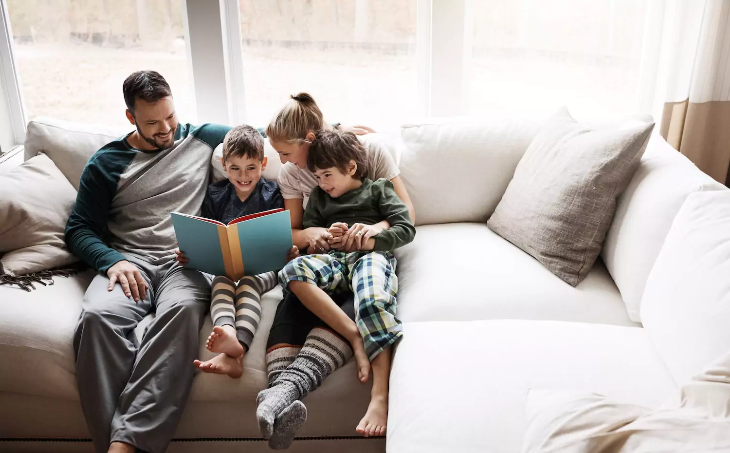A pastor and his family practice family worship together by reading a book on the couch together.