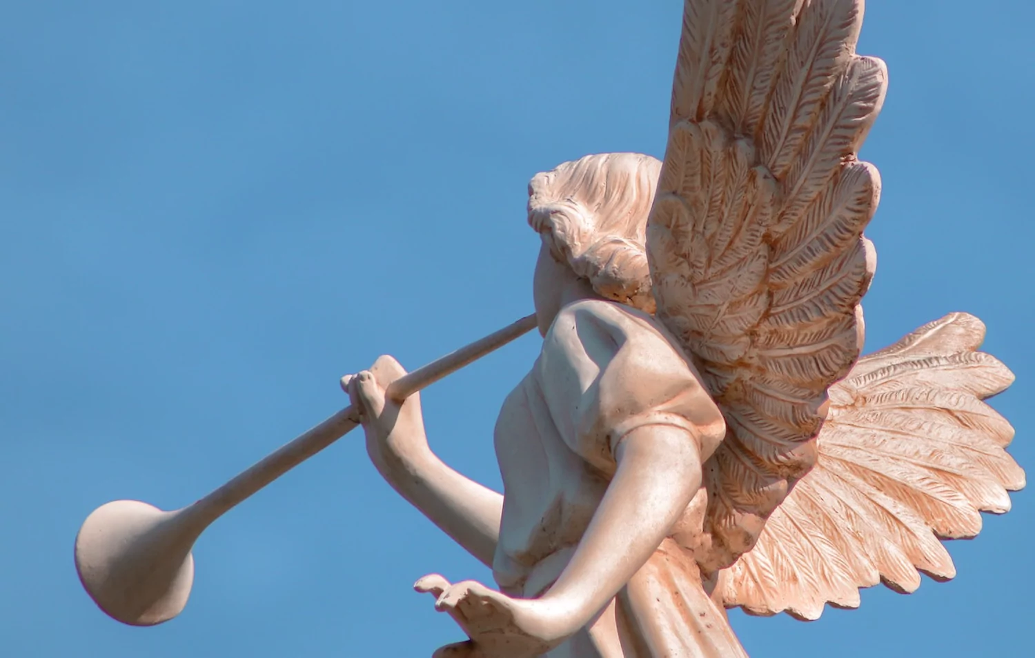 Statue of an angel blowing a long horn.