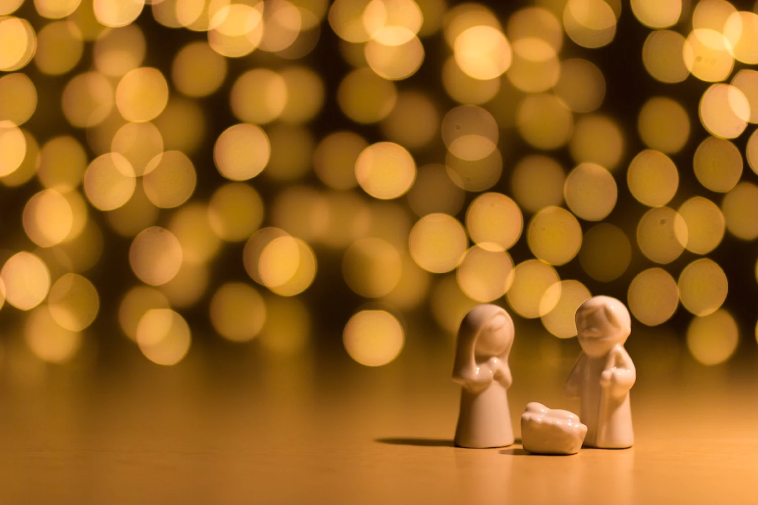 Figurines of Mary, Joseph, and Jesus in the manger in front of glowing lights.