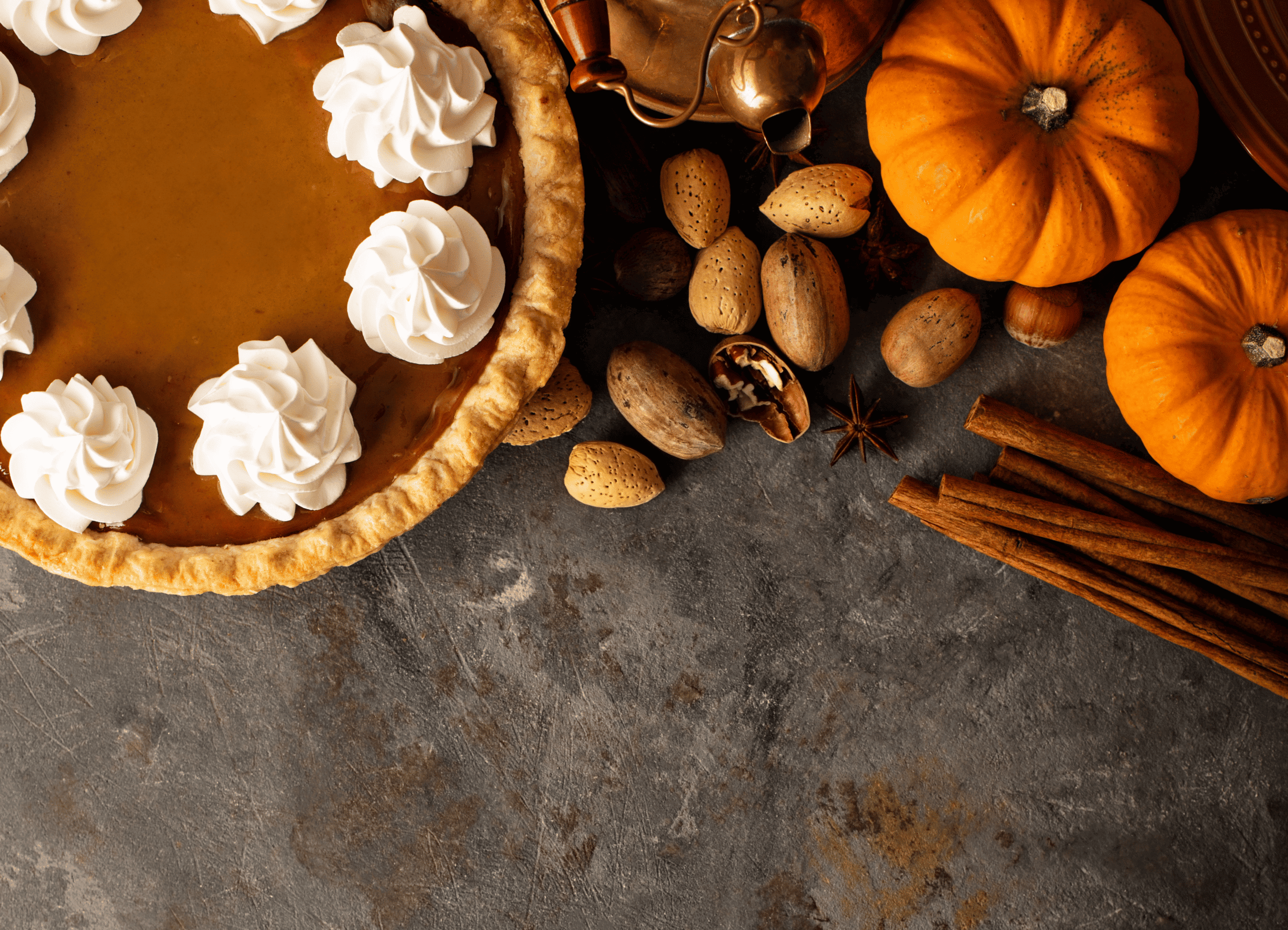 Pumpkin pie and other Thanksgiving ingredients laid on a gray countertop.