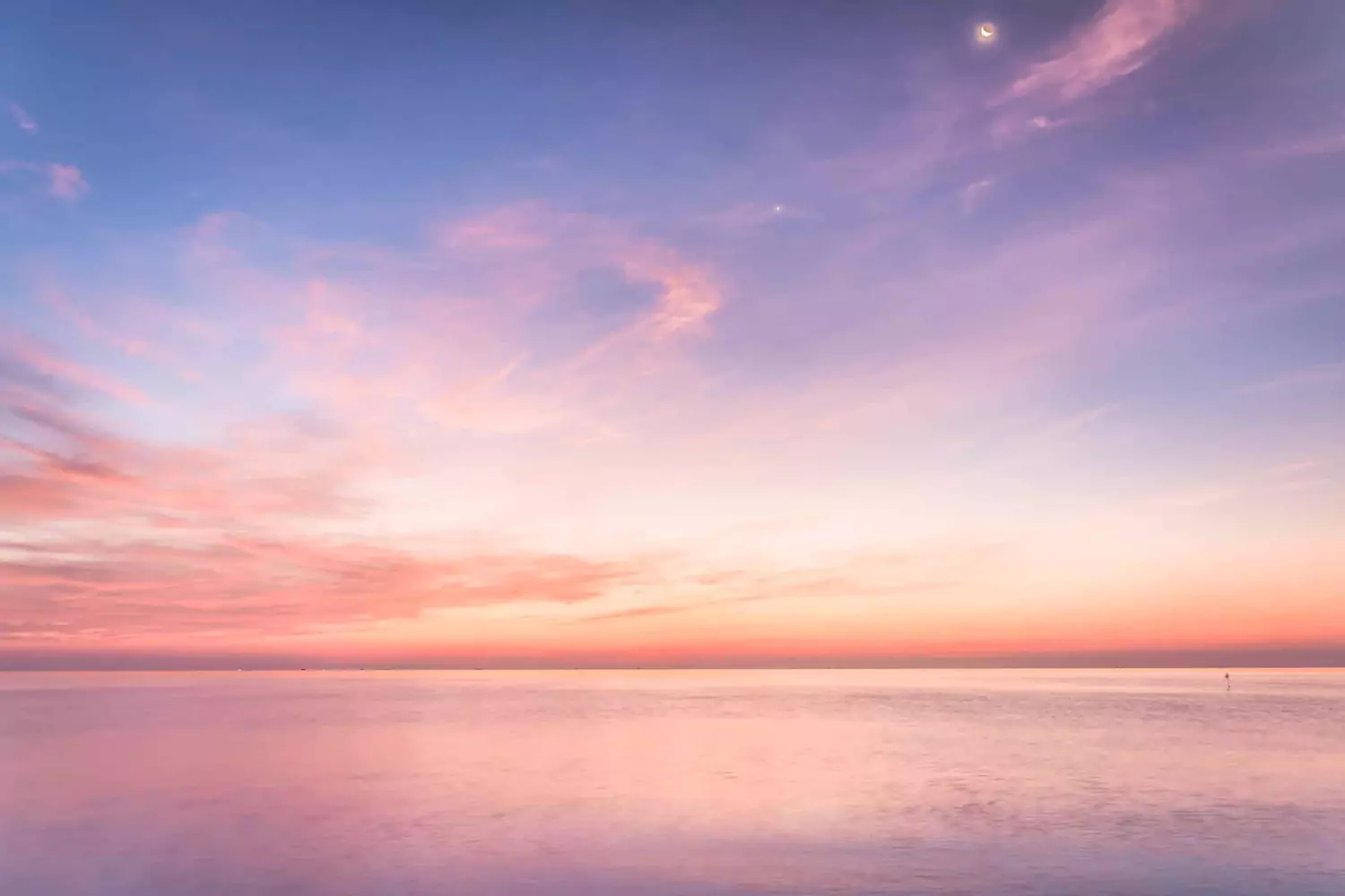 The sun sets pink over the sea.