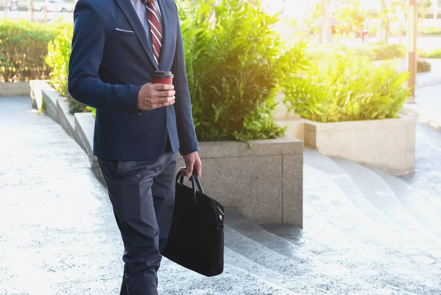 A pastor in a suit and red tie walks outside his church with latte in hand.