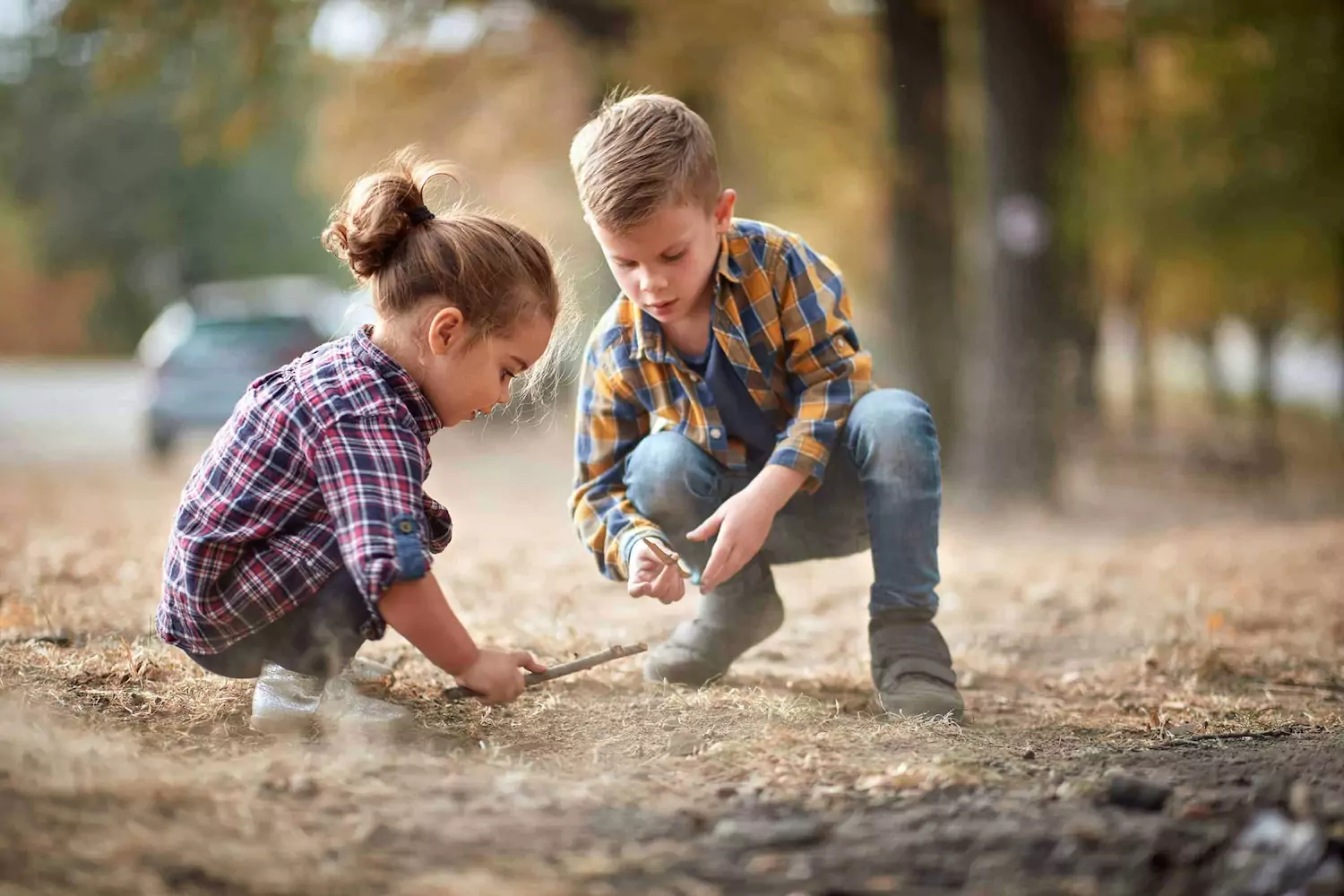 Two foster children, a little girl and boy, play in the dirt.