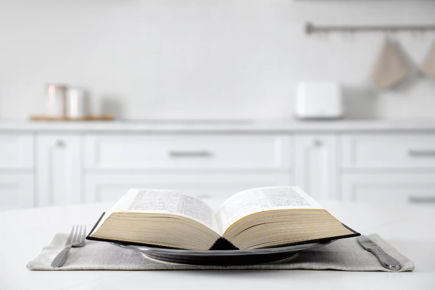 Bible sitting on plate with silverware, symbolizing the spiritual discipline or reaching the Bible.