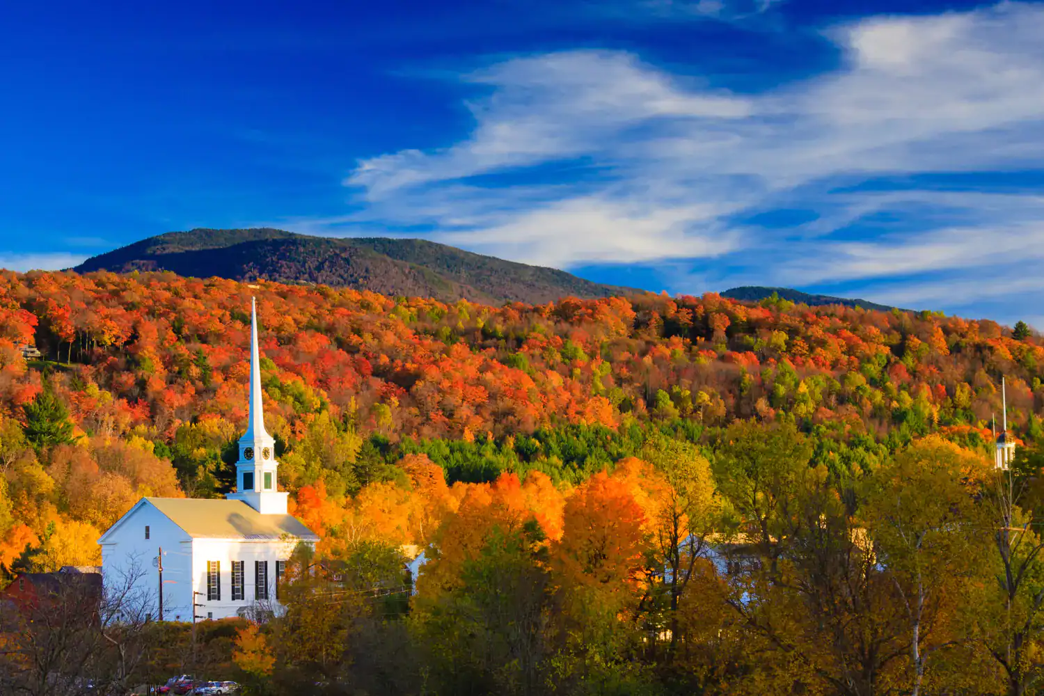 White church surrounded by vibrant fall foliage with mountains in the background, offering ministry encouragement during the fall busy season.