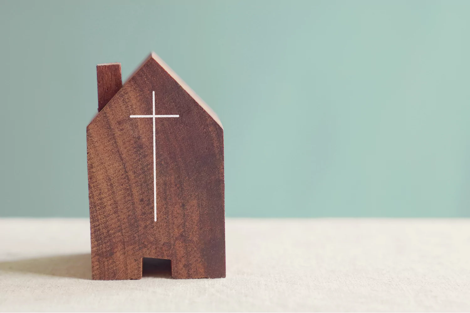 Small wooden house with a cross symbol, representing the humble beginnings and mission of church planting.