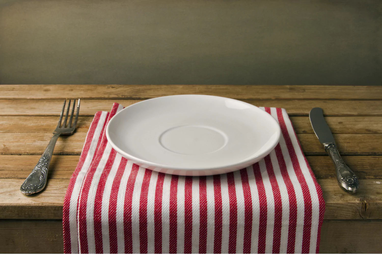 An empty white plate with silverware on a red-striped napkin, symbolizing “blessed are those who hunger and thirst for righteousness.”