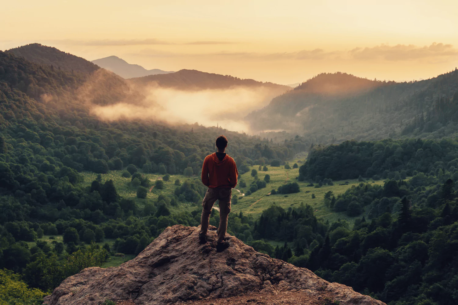 Young man standing on a mountain overlook at sunrise, symbolizing the hopeful journey of a new pastor.