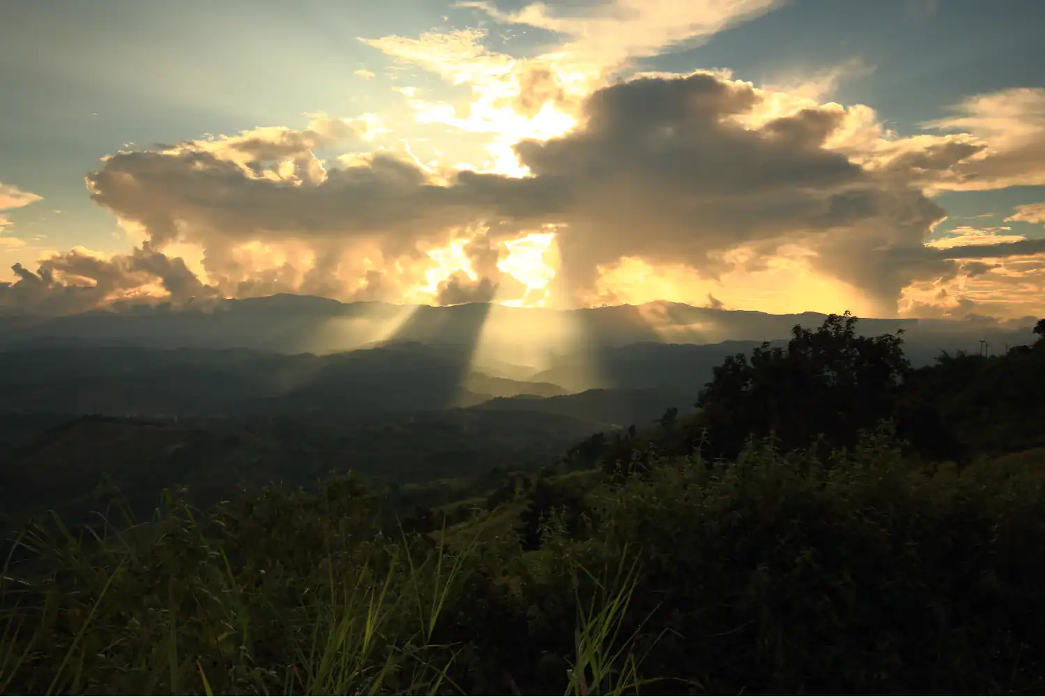 Sunlight streams through clouds over a quiet mountain valley, evoking the promise of hope and the truth that blessed are the merciful.