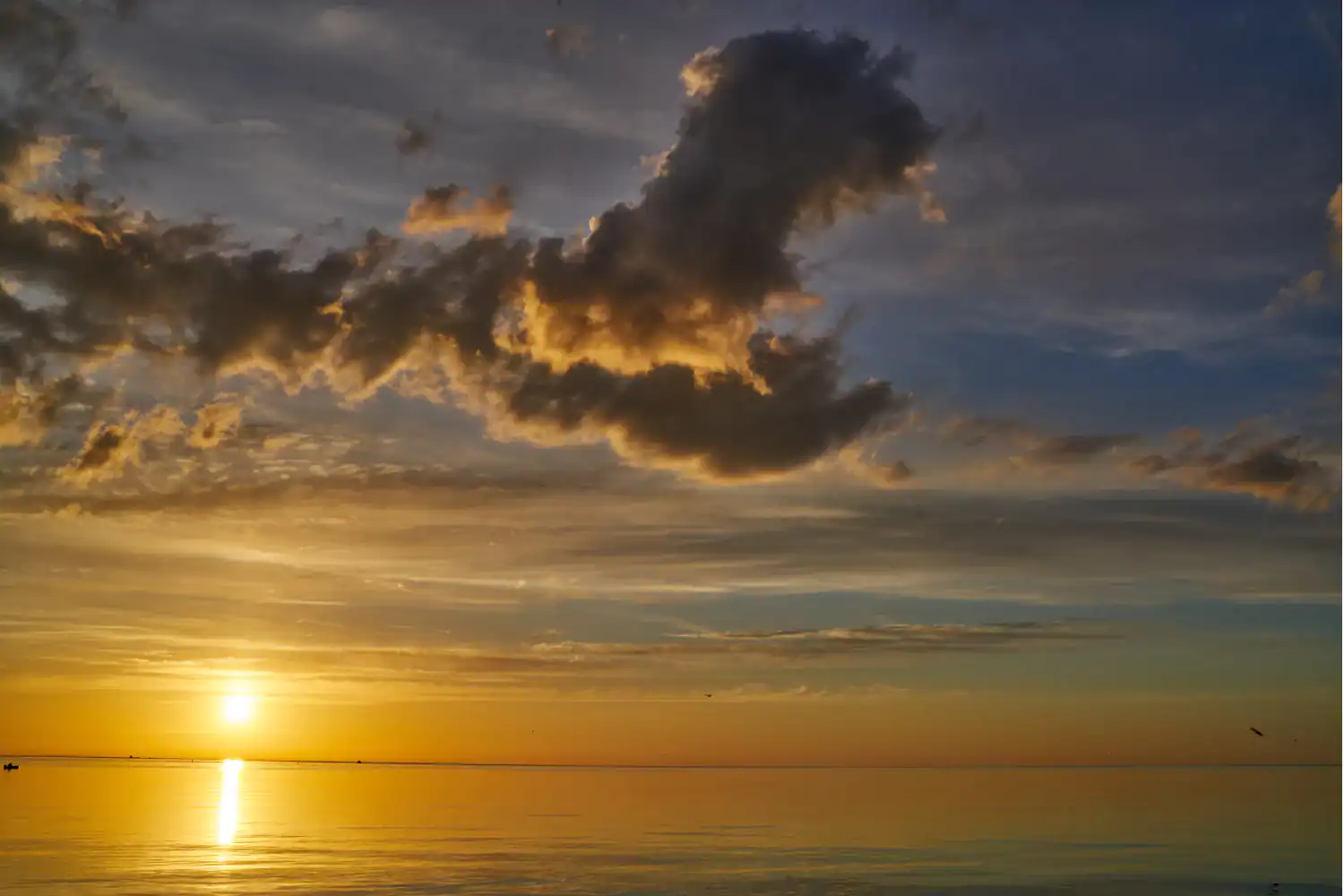 Golden sunrise over calm ocean waters with dramatic clouds, symbolizing the message "blessed are the pure in heart."