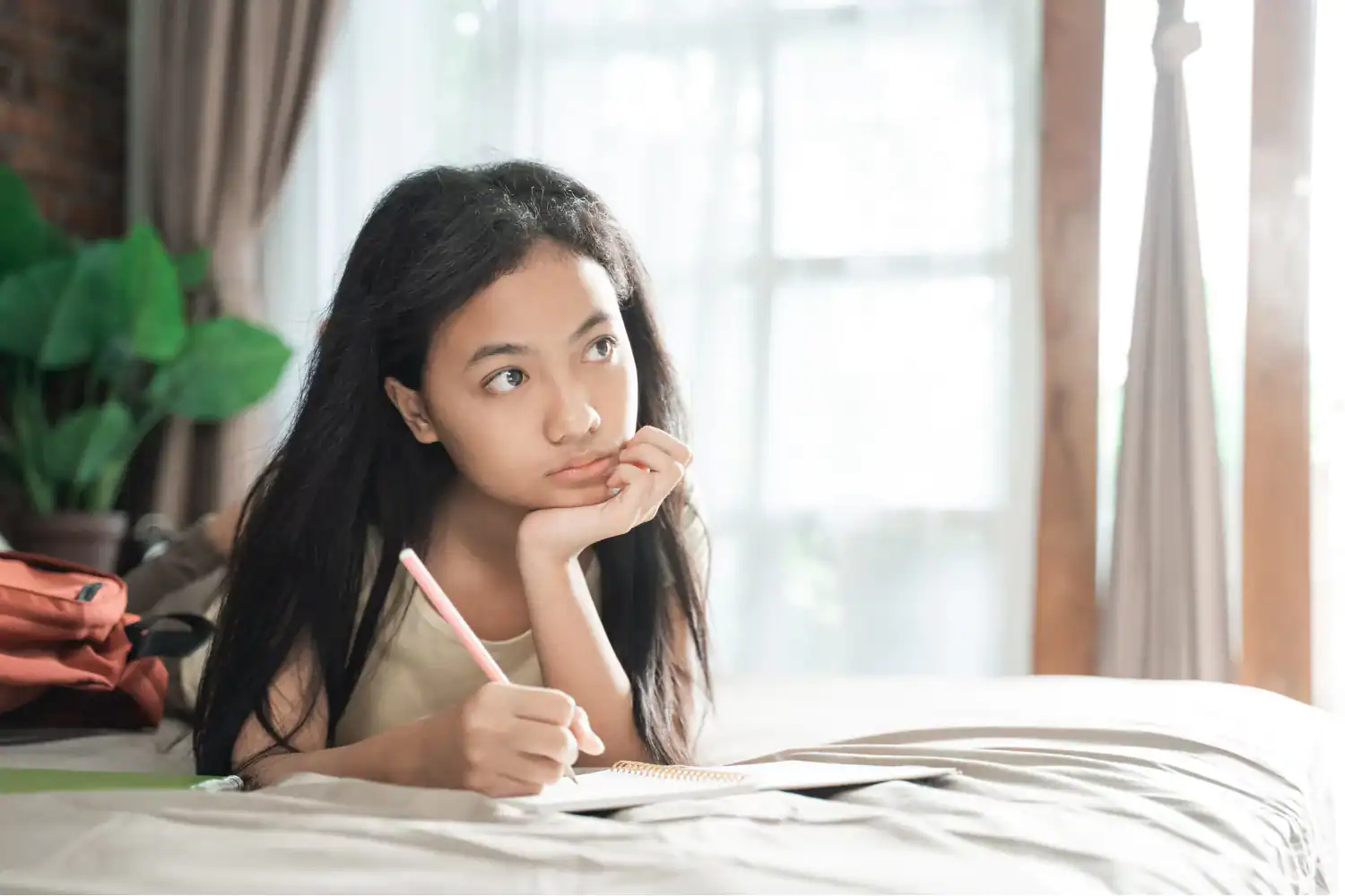 Teen girl lying on bed, journaling and reflecting, symbolizing helping kids find their identity.