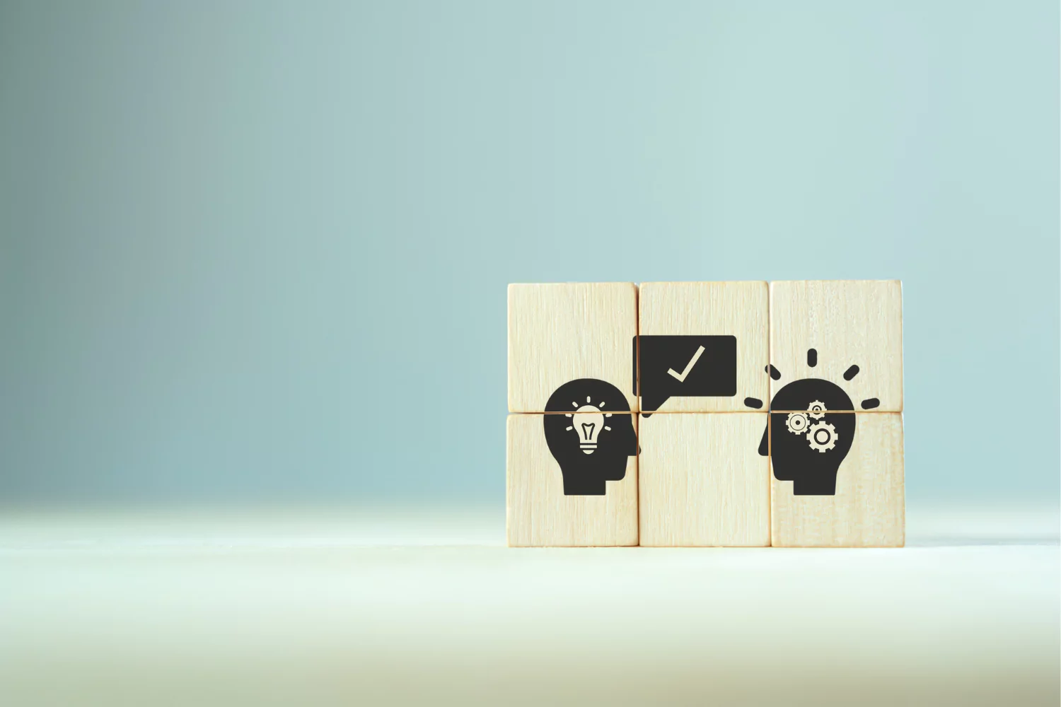 Wooden blocks with icons of heads, light bulbs, gears, and a checkmark, symbolizing how to receive criticism and grow from feedback.